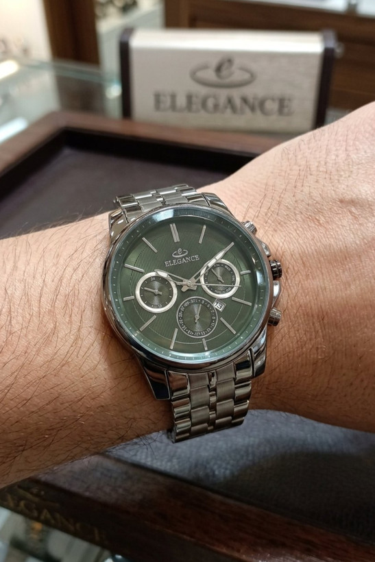 ساعت مچی مردانه الگانس با صفحه سبز روی مچ دست مردانه، جلوی دیسپلی برند ELEGANCE در فروشگاه ساعت